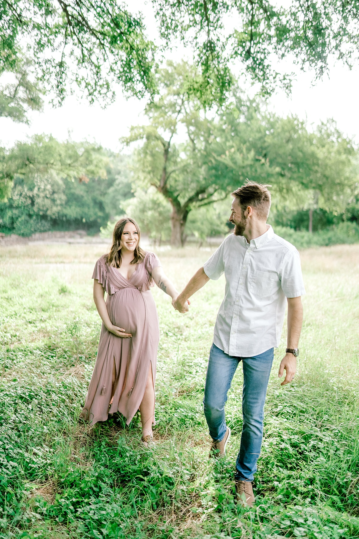 guy leading pregnant wife through field