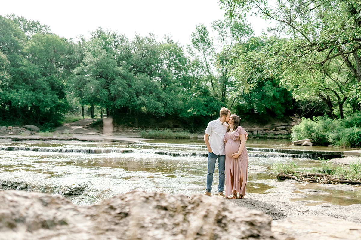 guy kissing girl while standing in creek bed