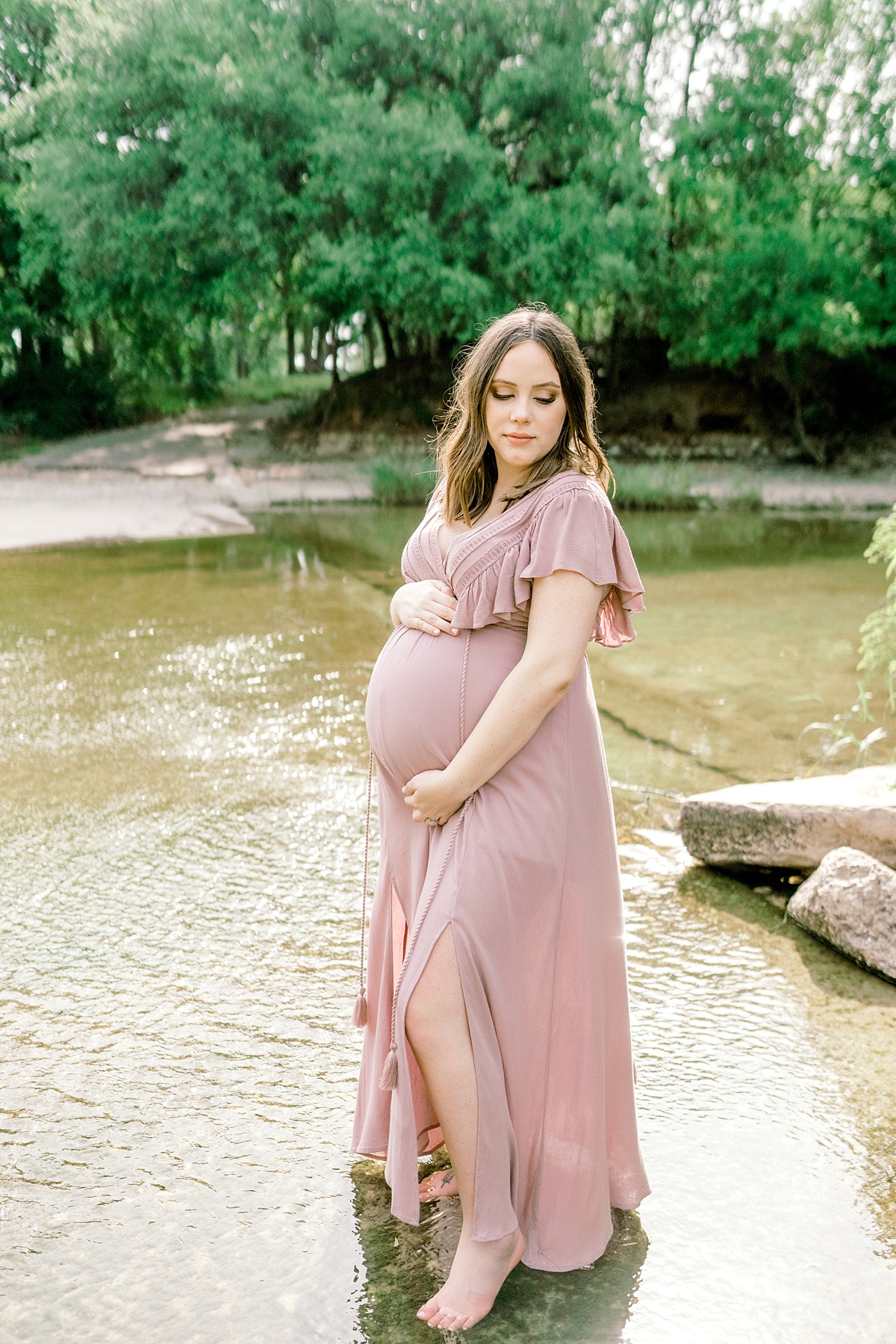 pregnant woman holding belly standing in water