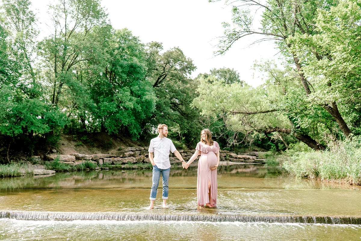 couple holding hands standing in creek