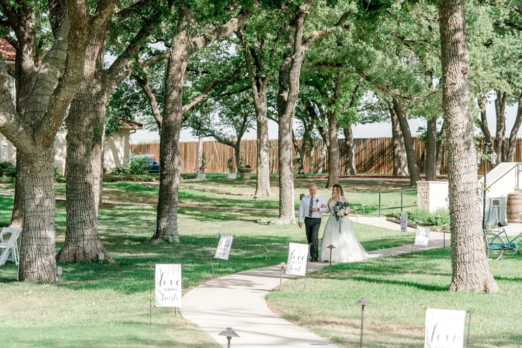 bride walking down aisle with father The Hamptons at Weatherford outdoor Texas wedding