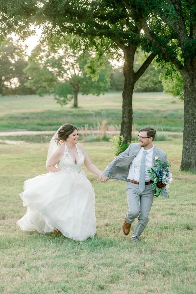 bride and groom holding hands and running through field The Hamptons at Weatherford wedding