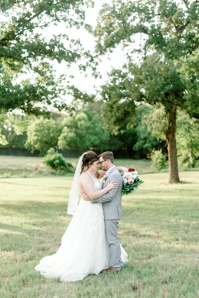 bride and groom embracing in field at the Hamptons at weatherford Texas wedding