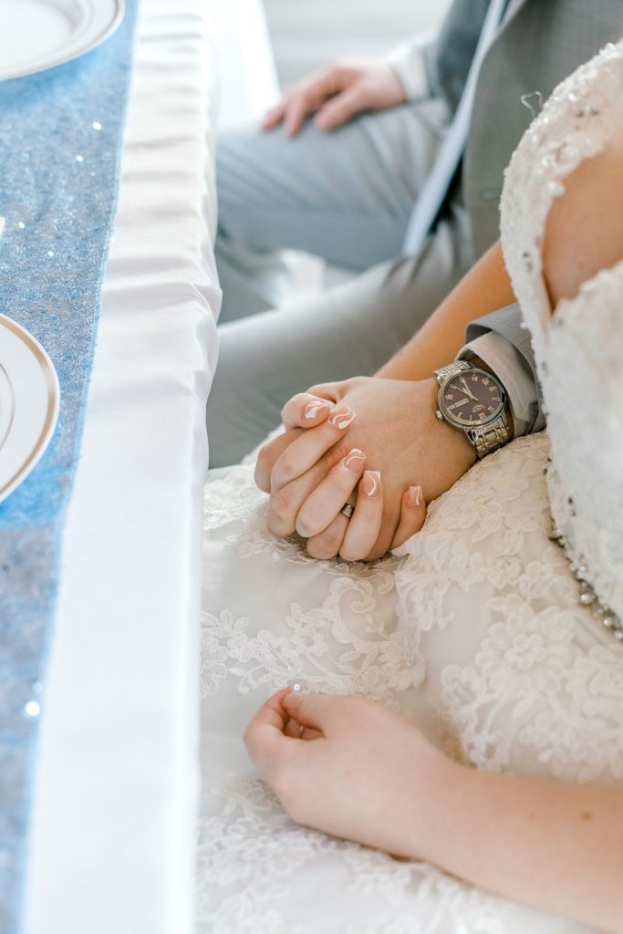 groom and bride holding hands at table- wedding nails