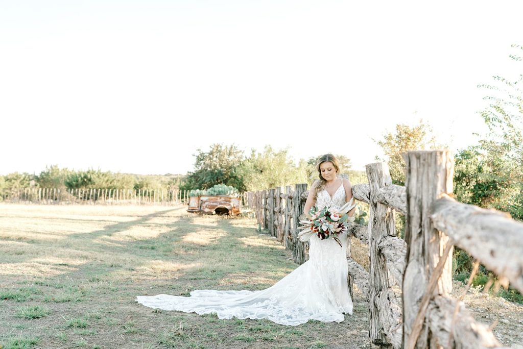 Bride leaning against fence post at Diamond H3 Ranch
