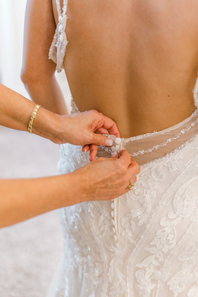 bride getting buttoned into wedding dress