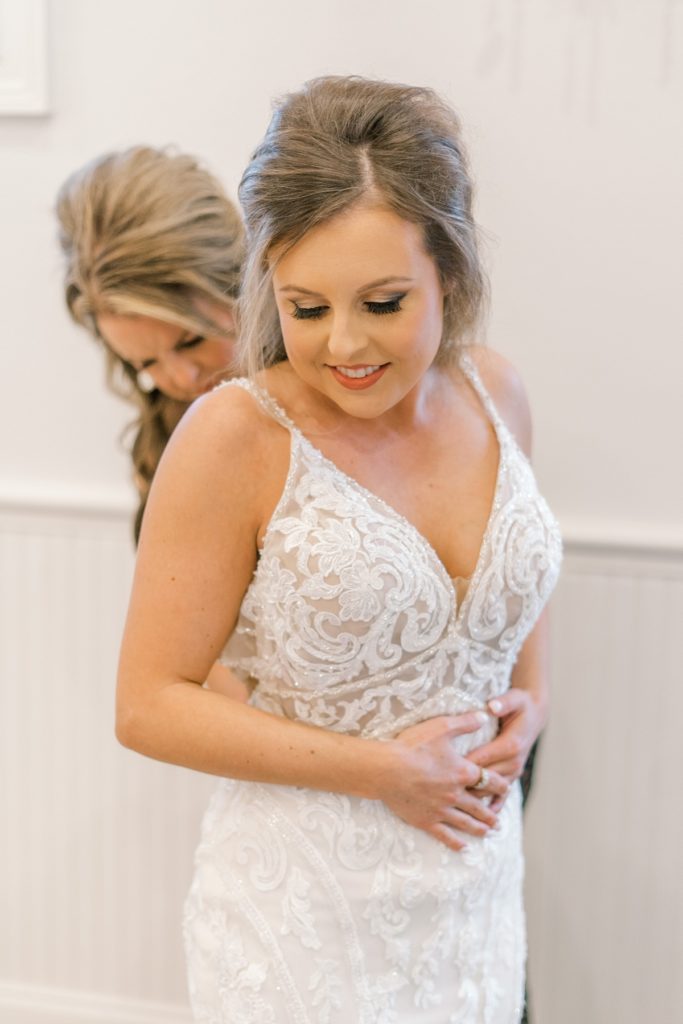 bride getting buttoned into wedding dress